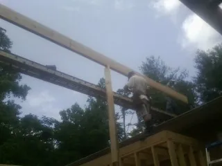 Carpenter setting a ridge beam over a new addition frame — Ice Dam Removal by Roofing Brothers in Wakeman
