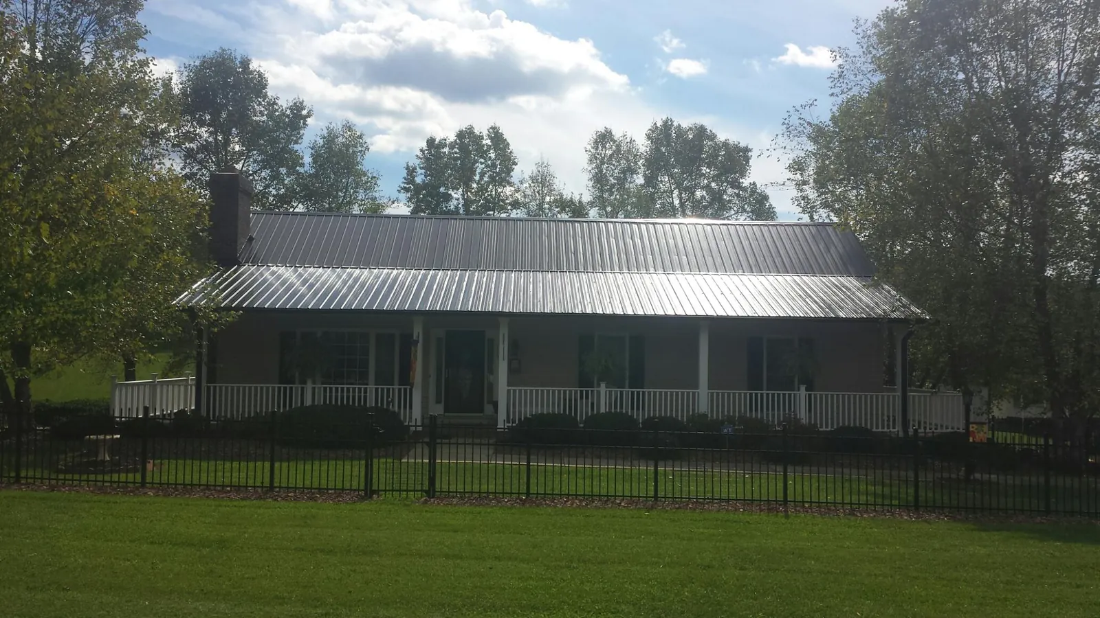 Gray metal roof on a brick ranch with a full width front porch — Gutter Guard Installation work by our crew in Wakeman