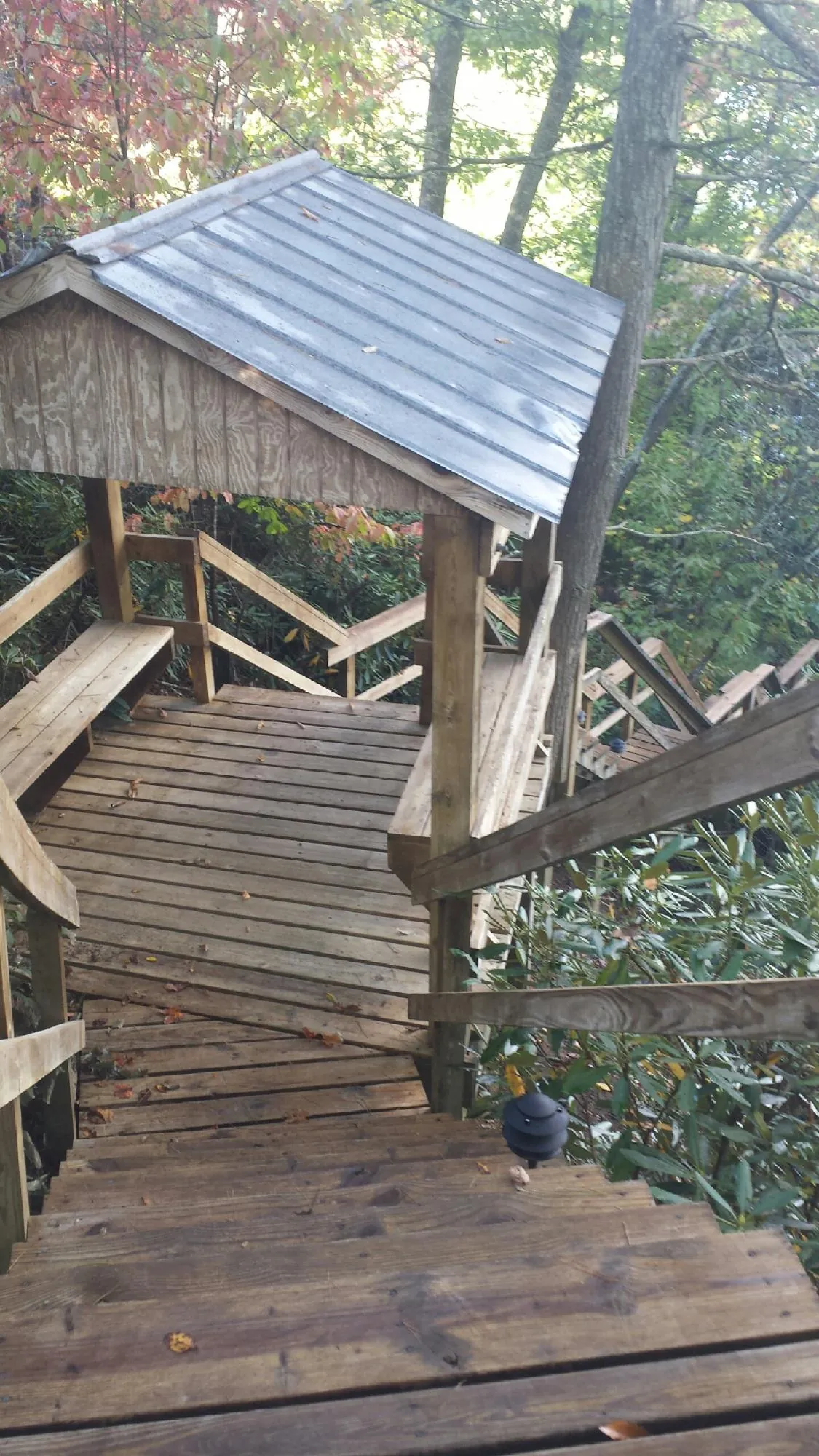 Metal roofed shelter over wooden steps on a wooded walkway — Skylight Repair & Installation work by our crew in Wakeman