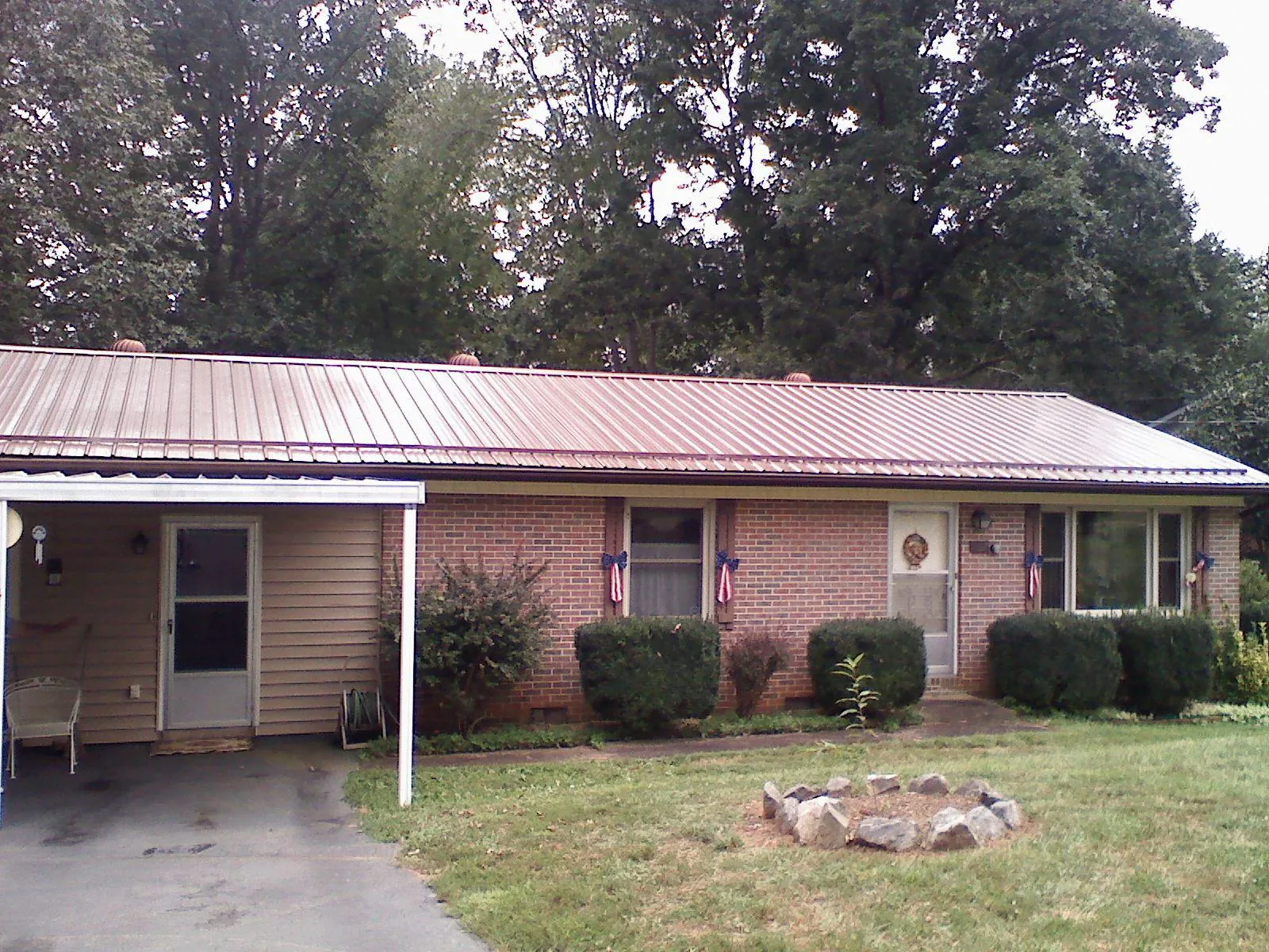 Bronze metal roof and carport on a brick ranch home — Roof Repair work by our crew in Wakeman