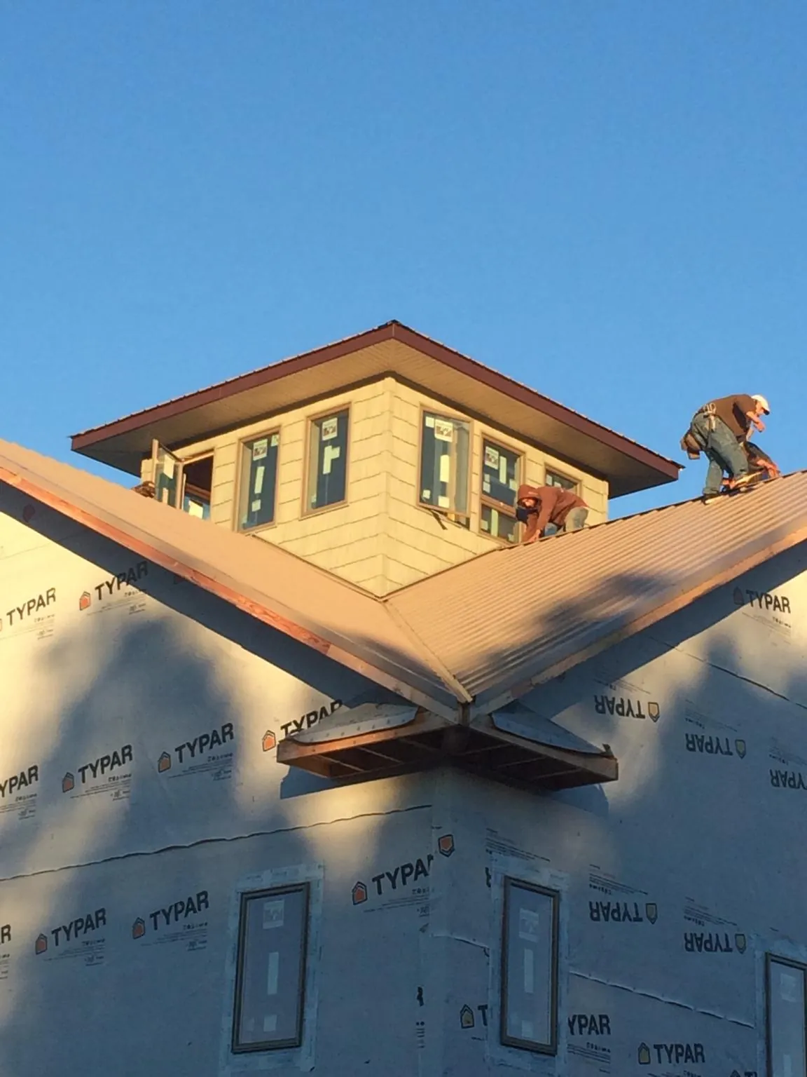 Roofers working around a rooftop cupola on a new metal roof at sunset — Roof Waterproofing in Wakeman by Roofing Brothers